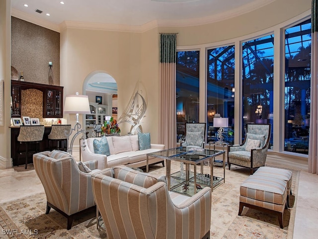 living area with wallpapered walls, a high ceiling, recessed lighting, arched walkways, and crown molding