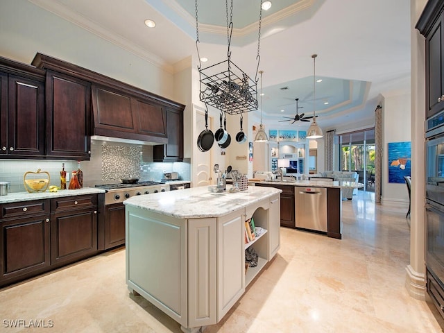 kitchen with dark brown cabinets, a center island with sink, ornamental molding, appliances with stainless steel finishes, and a raised ceiling