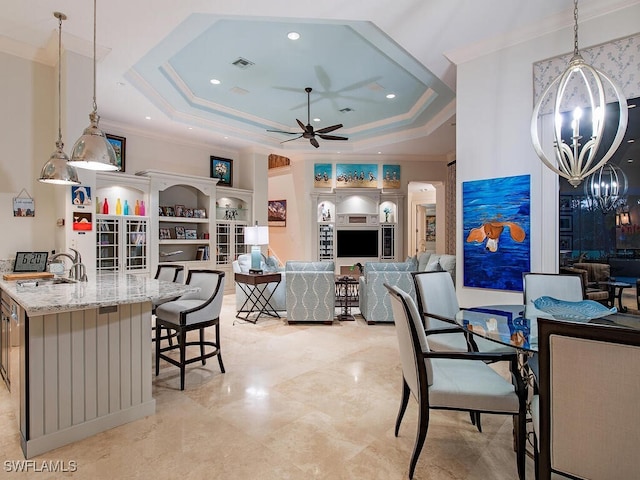 dining room with crown molding, a tray ceiling, ceiling fan with notable chandelier, and sink