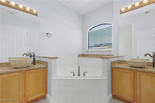 bathroom with vanity and tiled bath