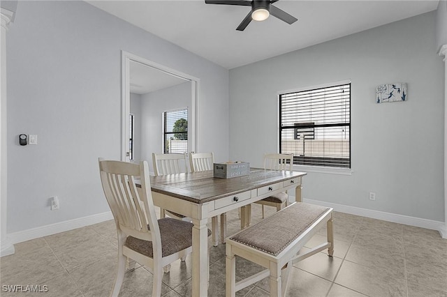 tiled dining space featuring ceiling fan and decorative columns