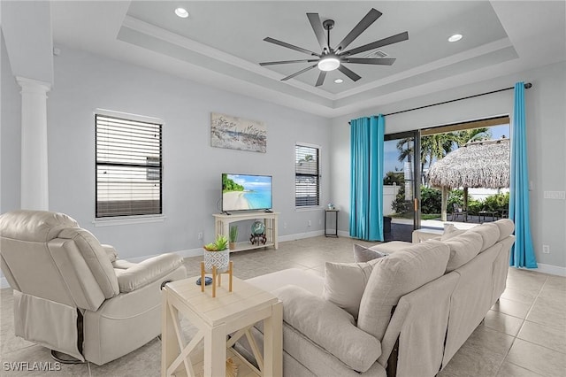 living room with plenty of natural light, a tray ceiling, and ornate columns