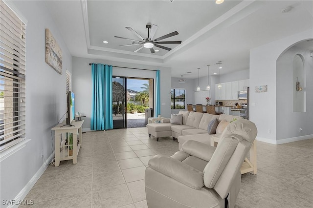 tiled living room with a raised ceiling and ceiling fan