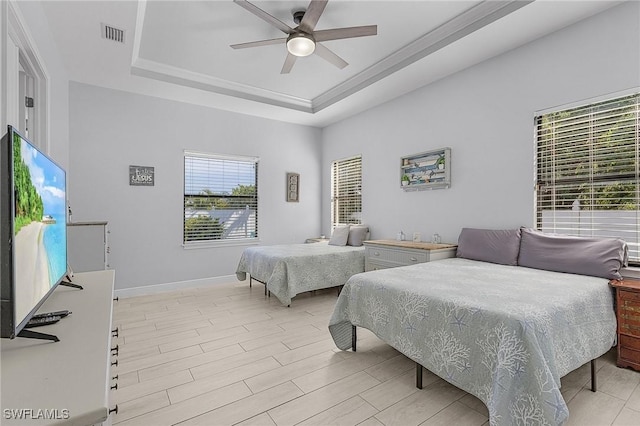 bedroom with a raised ceiling, ceiling fan, and light wood-type flooring