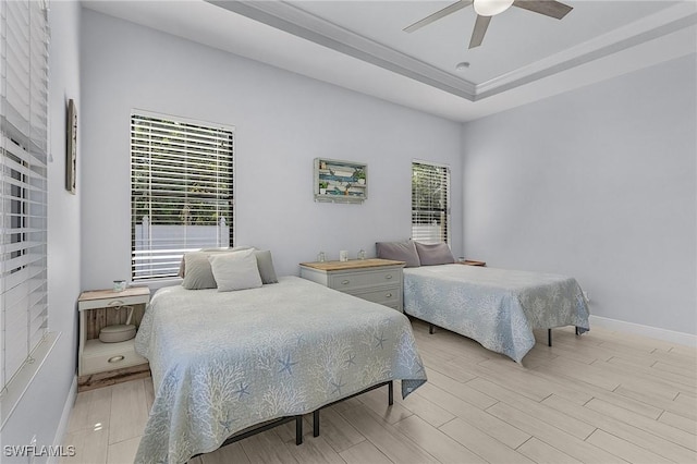 bedroom featuring ceiling fan, a tray ceiling, and light hardwood / wood-style floors