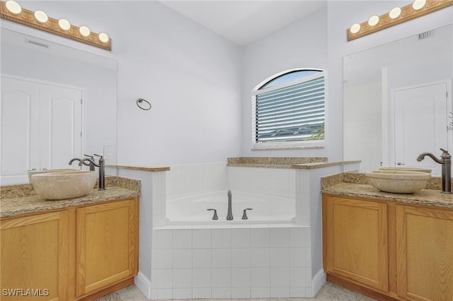 bathroom with vanity and tiled bath