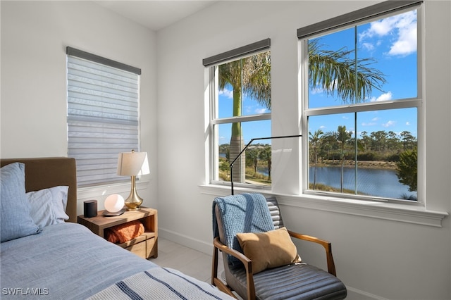 bedroom featuring wood finished floors, multiple windows, baseboards, and a water view