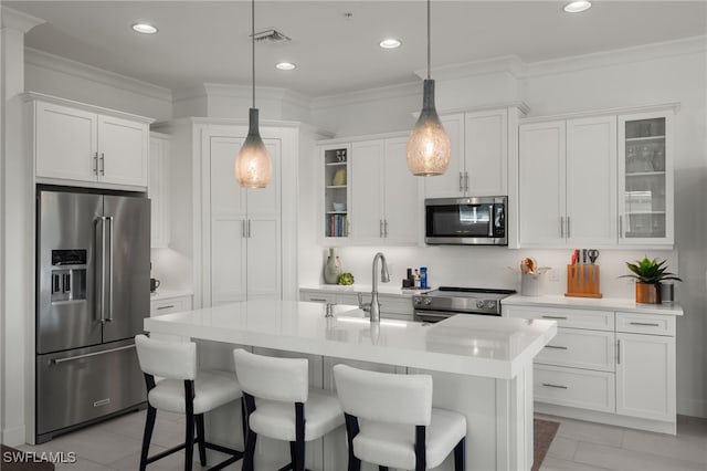 kitchen featuring a breakfast bar area, ornamental molding, stainless steel appliances, light countertops, and white cabinets