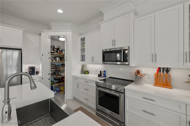 kitchen featuring white cabinetry, stainless steel appliances, crown molding, and a sink