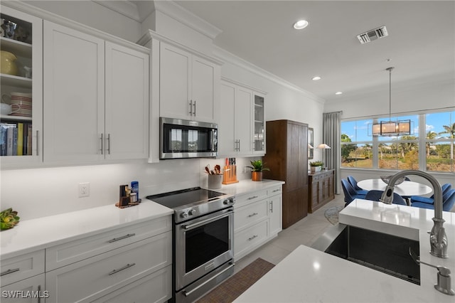 kitchen featuring visible vents, white cabinetry, stainless steel appliances, crown molding, and glass insert cabinets