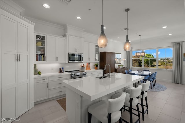 kitchen with a kitchen island with sink, a sink, stainless steel appliances, light countertops, and crown molding