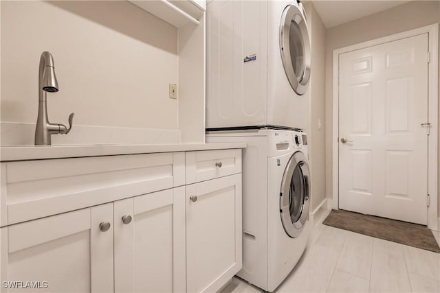 washroom with cabinets, stacked washer / drying machine, and light tile patterned flooring