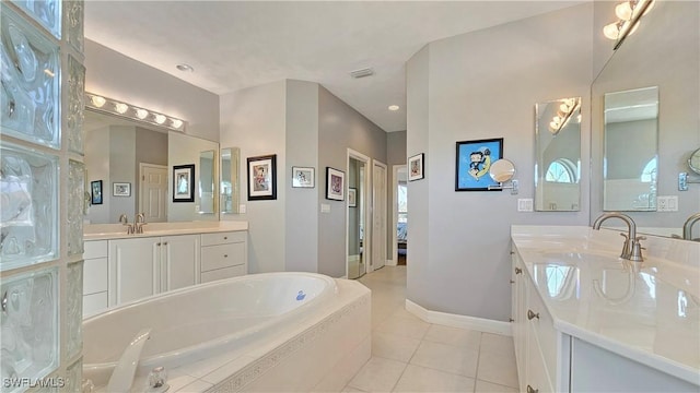 bathroom featuring tile patterned flooring, vanity, and tiled bath