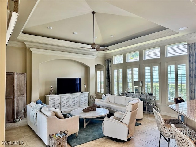 living room with a tray ceiling, arched walkways, crown molding, light tile patterned floors, and a high ceiling