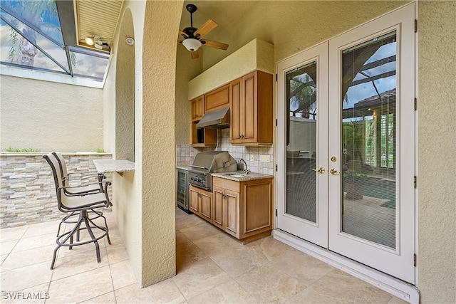 9411 Monteverdi Way, Fort Myers, FL 33912 - kitchen featuring a textured wall, under cabinet range hood, healthy amount of natural light, brown cabinets, and tasteful backsplash