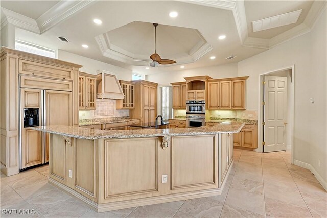 9411 Monteverdi Way, Fort Myers, FL 33912 - kitchen featuring premium range hood, paneled fridge, a large island with sink, ornamental molding, and stainless steel double oven