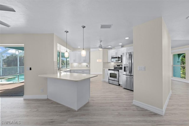 kitchen with hanging light fixtures, stainless steel appliances, white cabinets, and ceiling fan