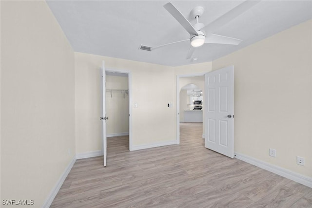 unfurnished bedroom with ceiling fan, a spacious closet, light hardwood / wood-style floors, and a closet