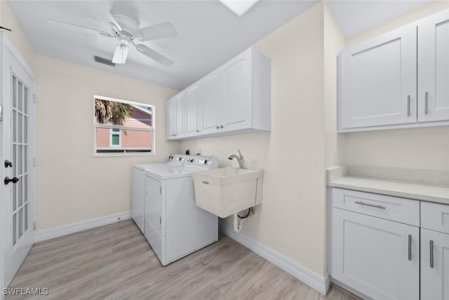 laundry room featuring cabinets, washing machine and dryer, sink, and light wood-type flooring