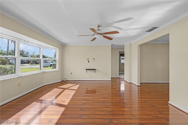 spare room featuring ceiling fan, wood-type flooring, ornamental molding, and a textured ceiling