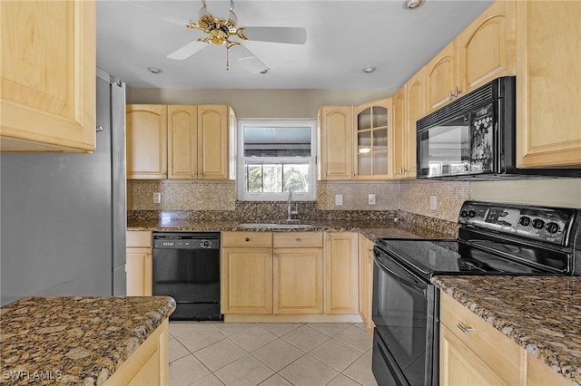 kitchen featuring light tile patterned flooring, light brown cabinetry, sink, dark stone counters, and black appliances