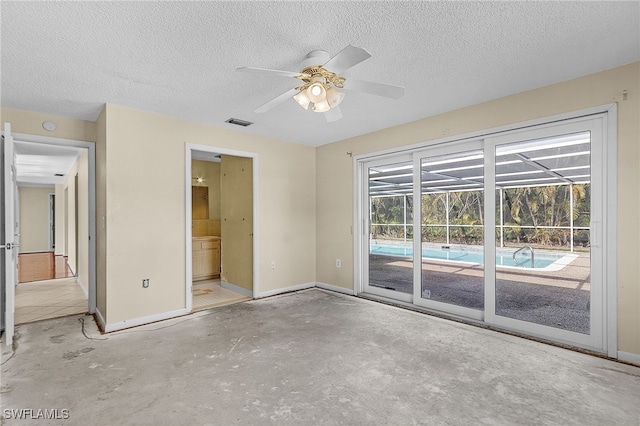 interior space with ensuite bathroom, access to exterior, concrete flooring, and a textured ceiling