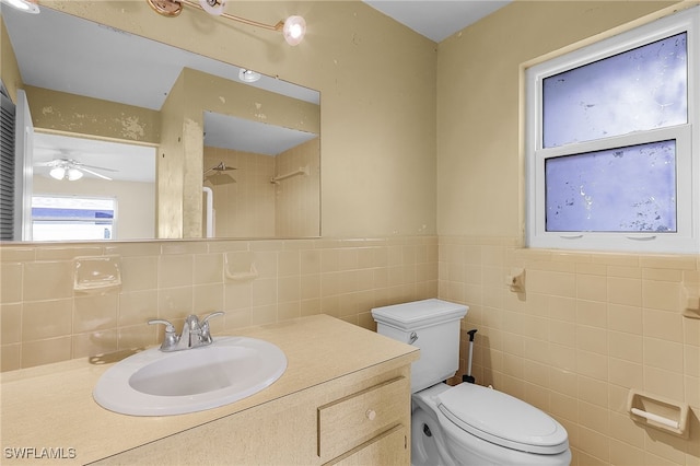 bathroom featuring ceiling fan, vanity, toilet, and tile walls