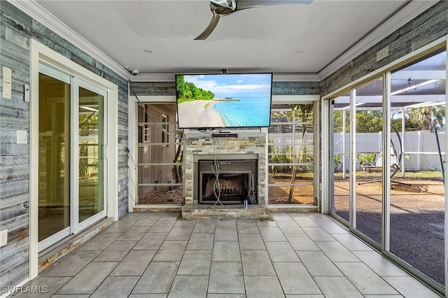 unfurnished sunroom featuring ceiling fan and an outdoor stone fireplace