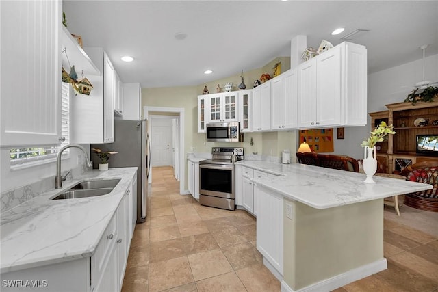 kitchen featuring appliances with stainless steel finishes, sink, white cabinets, light stone counters, and kitchen peninsula