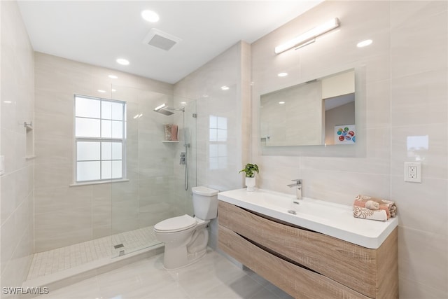 bathroom with tile walls, vanity, toilet, and tiled shower