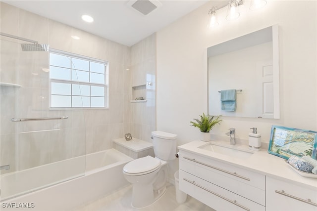 full bathroom featuring tiled shower / bath, vanity, and toilet