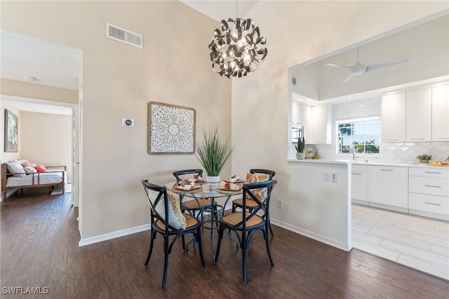 dining room featuring hardwood / wood-style floors, ceiling fan with notable chandelier, sink, and a textured ceiling