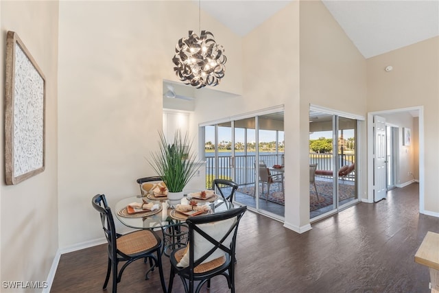 dining room with a water view, dark hardwood / wood-style floors, high vaulted ceiling, and a notable chandelier