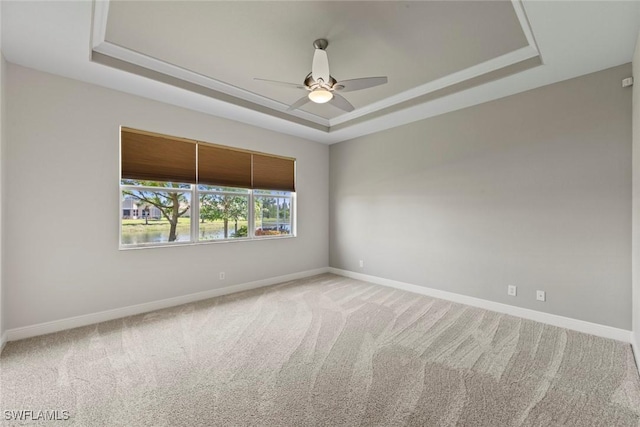 empty room featuring light carpet, a raised ceiling, and ceiling fan