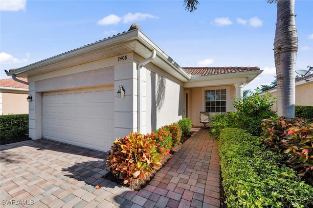 exterior space featuring a tiled roof, decorative driveway, an attached garage, and stucco siding