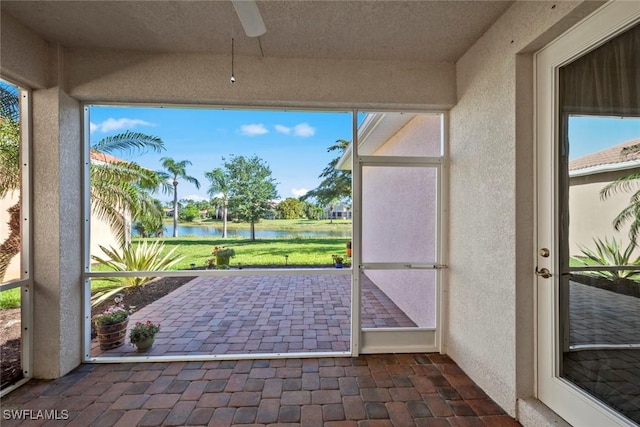 unfurnished sunroom featuring a water view, ceiling fan, and a healthy amount of sunlight