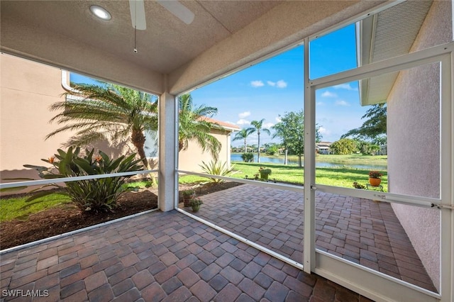 unfurnished sunroom with a water view and ceiling fan