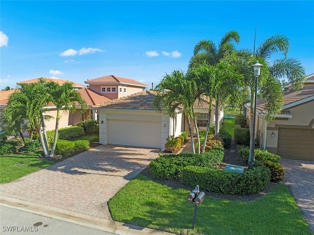 view of front of house featuring decorative driveway, an attached garage, a tile roof, and stucco siding