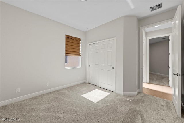 unfurnished bedroom with light colored carpet and a closet