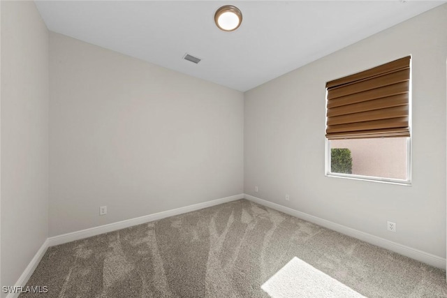 spare room with carpet, visible vents, and baseboards