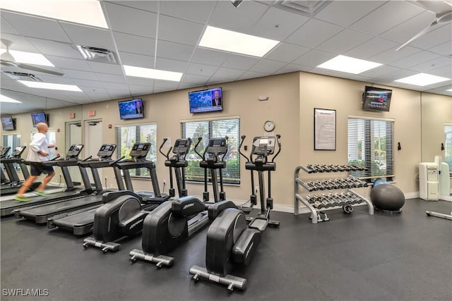 exercise room with a paneled ceiling, baseboards, and visible vents