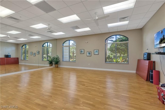 exercise area with ceiling fan, plenty of natural light, a paneled ceiling, and light hardwood / wood-style floors