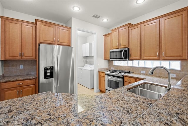 kitchen featuring tasteful backsplash, visible vents, appliances with stainless steel finishes, a sink, and separate washer and dryer