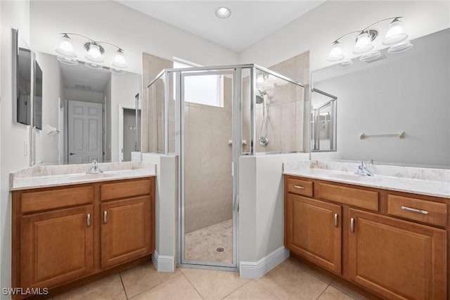 full bath featuring a shower stall, two vanities, a sink, and tile patterned floors