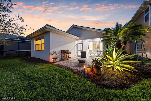 back of property with a lawn, a patio, and stucco siding