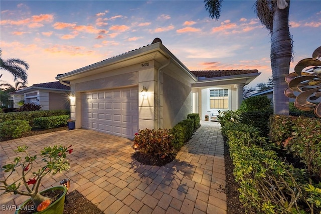 view of front facade with decorative driveway, an attached garage, and stucco siding