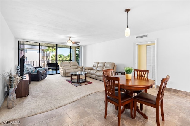 carpeted dining area featuring a wall of windows and ceiling fan