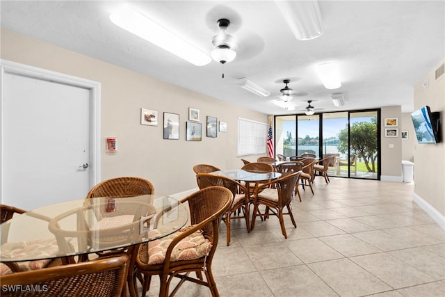 dining area featuring light tile patterned flooring, ceiling fan, and a wall of windows