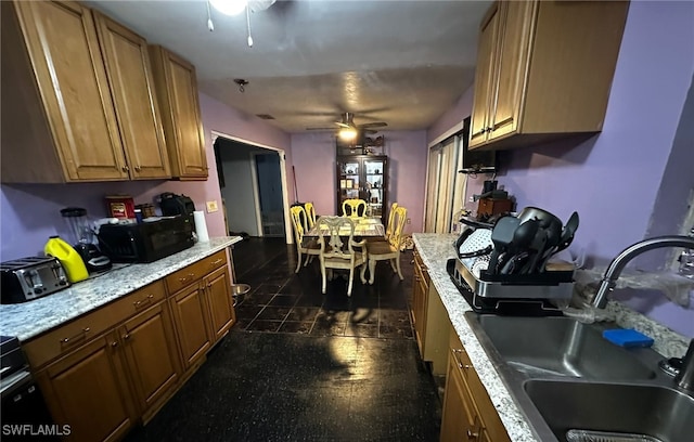 kitchen with sink, light stone counters, and ceiling fan