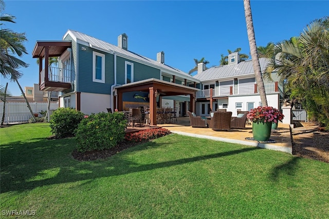 back of property with a balcony, a yard, an outdoor hangout area, and a patio area